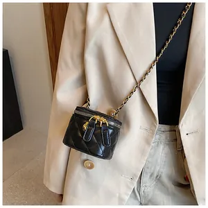Detail of quilted leather mini vanity bag with gold chain strap on beige blazer