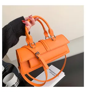 Detail einer hellorangen Handtasche aus Kunstleder mit Doppelgriffen und dunklen Metallteilen