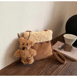 Detailed view of brown suede crossbody bag with fleece trim and teddy bear charm