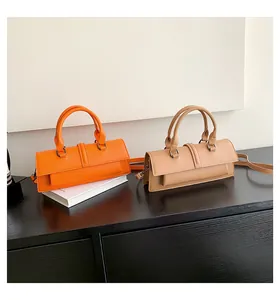 Detailansicht rechteckiger Taschen aus mattem Leder in Orange und Beige auf Holz