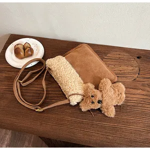 Detail of faux suede and shearling crossbody bag with a cute plush bear charm on wood