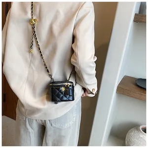 Rear view of a model wearing a mini black quilted leather chain bag with gold hardware