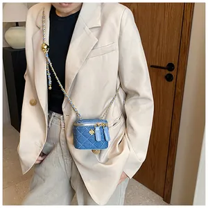 Close-up of quilted denim mini bag with gold camellia flower and chain strap detail