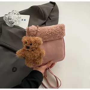 Detail of pink faux suede crossbody bag with shearling trim and cute brown bear charm