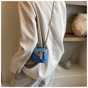Detail of mini denim crossbody bag with camellia zipper and golden chain strap