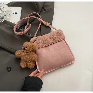 Detail of pink faux shearling and suede crossbody bag with cute brown bear charm