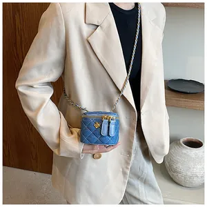 Detailed view of mini blue denim vanity bag with gold chain and camellia flower