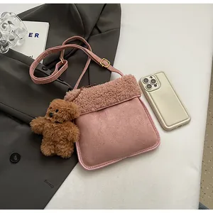 Detail of pink faux shearling and suede crossbody bag with teddy bear charm and gold buckle