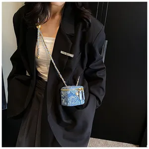 Detail of blue denim mini box bag with floral pattern and gold metal chain strap