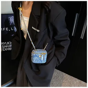 Detail of blue denim mini bag with quilted pattern and gold camellia flower charm