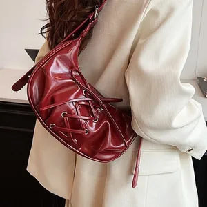Glossy dark red crescent shoulder bag with lace-up ribbon design and metal eyelets
