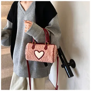 Roze lamswol Boston tas met rode banden en hartpatroon gedragen door een model