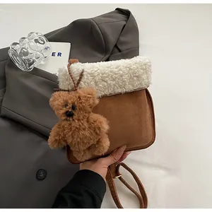 Detailed shot of shearling-trimmed suede crossbody bag with cute plush bear charm