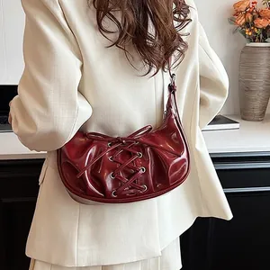 Burgundy crescent bag with lace-up details worn by model in off-white blazer