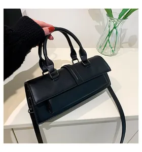 Details einer schwarzen Handtasche mit Doppelgriff und verstellbarem Schultergurt