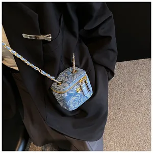 Close-up of denim vanity case bag featuring floral embroidery and gold chain strap