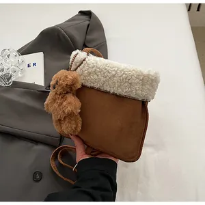 Detail of a brown faux suede tote bag with white lamb wool trim and a cute plush bear charm