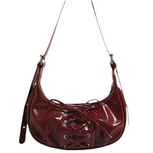 Deep red patent leather crescent shoulder bag with bow tie cross-straps and glossy finish