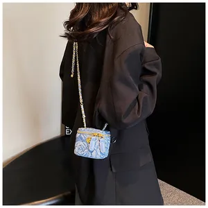 Chic mini blue denim box crossbody bag with camellia pattern worn by a model in a suit