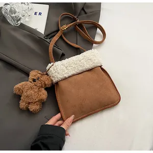 Detail of faux suede shoulder bag with plush shearling trim and cute bear charm