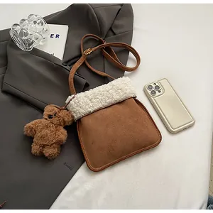 Detail of faux suede crossbody bag with fluffy fleece trim and cute bear charm