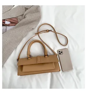Detailansicht der khakifarbenen Handtasche mit Schultergurt und Griff auf weißem Stoff