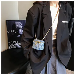 Detailed macro view of denim mini crossbody bag with golden chain and floral charm