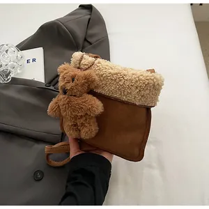 Detailed view of the brown faux suede handbag with plush shearling trim and cute bear charm