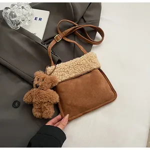 Detail of faux suede shoulder bag with plush shearling trim and cute brown bear charm