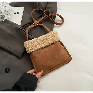Detail of brown suede crossbody bag with white sherpa trim on dark grey blazer
