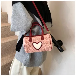 Detail van roze pluche Boston tas met hart-patch en rode schouderband