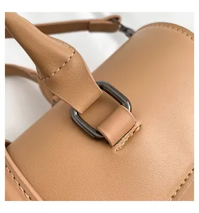 Detailaufnahme des braunen Leder-Handtaschengriffs mit Nähten und Metallschnallen