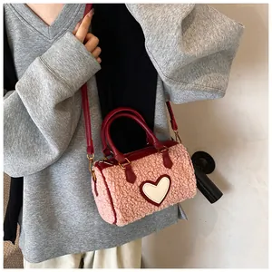 Detail van roze teddy tas met rode lederen bies en een witte hartvormige patch