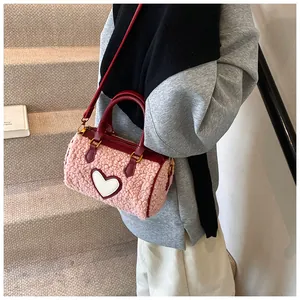 Detail van roze lamswollen tas met witte hart-patch en rode lederen schouderriem voor dames