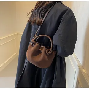 Deep brown matte bucket bag with knot detail worn with a black trench coat