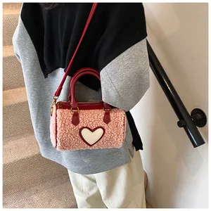 Detail van roze lamswollen Boston tas met wit hartje gedragen door een model