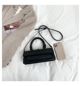 Makroaufnahme einer minimalistischen schwarzen Handtasche aus mattem Leder mit dünnem Gurt