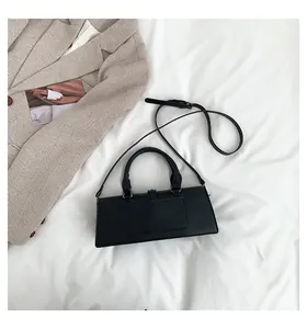 Detailansicht einer schwarzen Handtasche auf weißem Stoff mit einem Blazer als Requisite