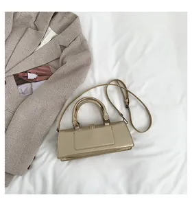 Detail einer champagnergoldenen Lederhandtasche auf Stoff und Blazer-Hintergrund