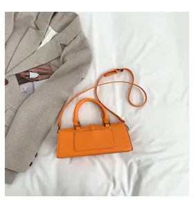 Flache Darstellung der hellorangen Ledertasche auf weißem Stoff mit grauem Blazer