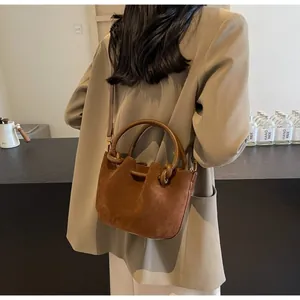 Close-up of vintage brown suede bucket bag with cylindrical leather handle and fine texture
