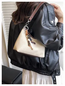 Détail du sac en toile avec garniture en cuir marron et pendentif en perles de bois unique