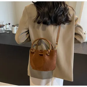 Detail of vintage brown suede bucket bag featuring premium matte texture and round handle