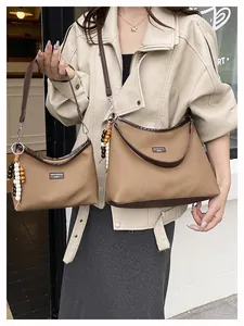 Détail de sacs bandoulière en feutre marron avec finitions cuir et perles en bois
