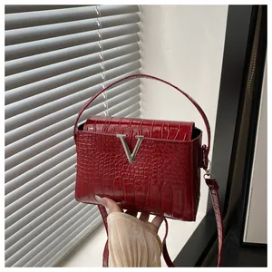Close-up of red crocodile-embossed handbag with silver V-shaped buckle and fine texture