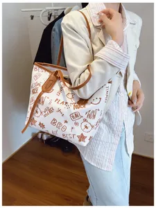Detail of large tote bag with cartoon graffiti print and brown PU leather straps