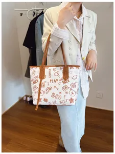 Detail of large tote bag featuring cartoon bear graffiti and brown leather handles