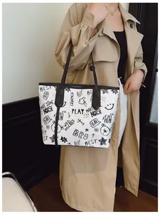 Detail of white graffiti tote bag with black handles and street art patterns on a model