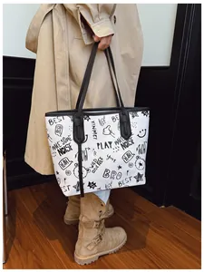 Detailed close-up of large tote bag with creative graffiti prints and black slim handles