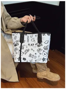 Detail shot of white tote bag with black artistic graffiti patterns and shoulder strap